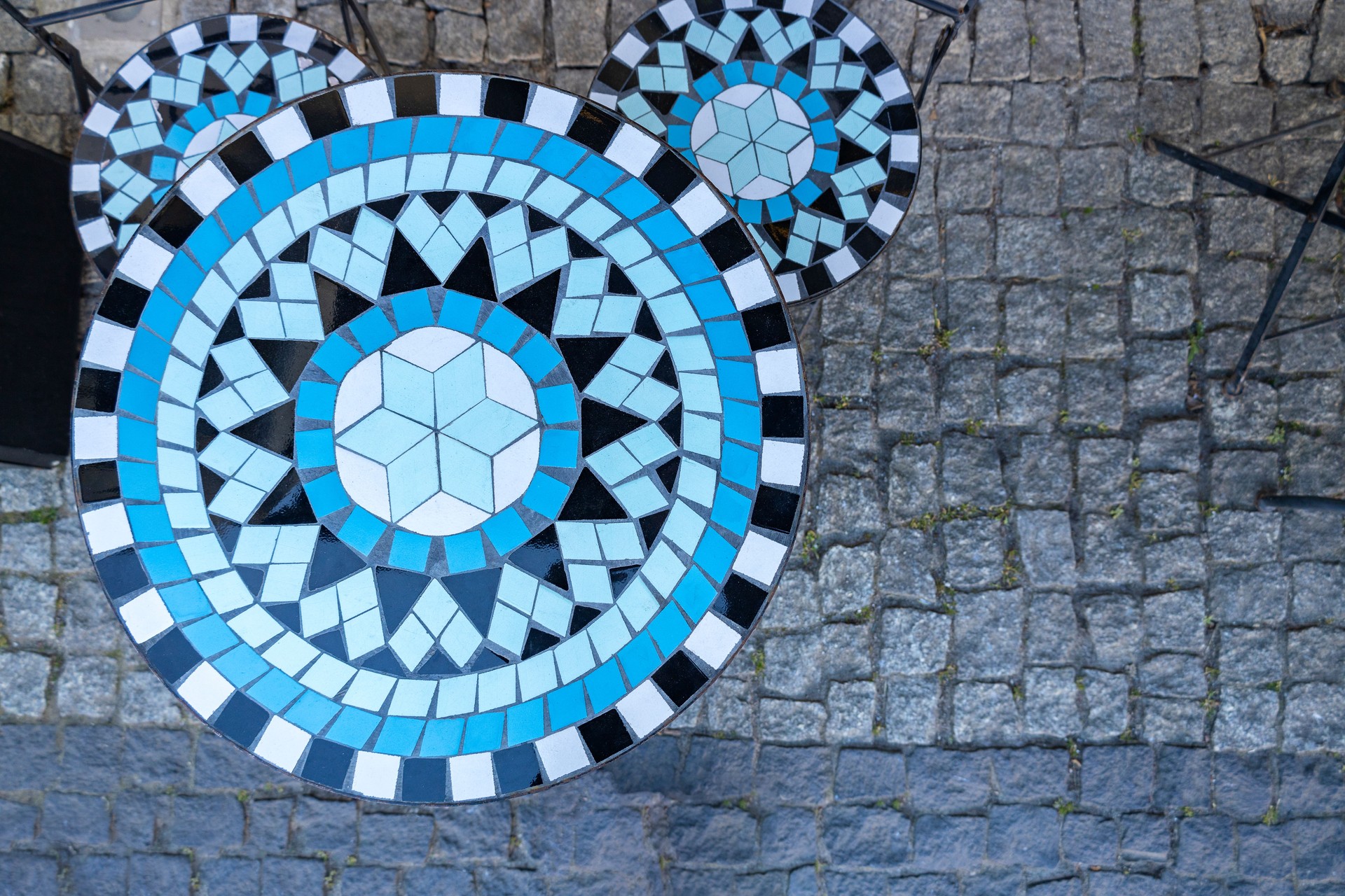 Mosaic and metal furniture at cafe. Coffee table and chairs made using a mosaic style. Table and chairs standing on paving stones